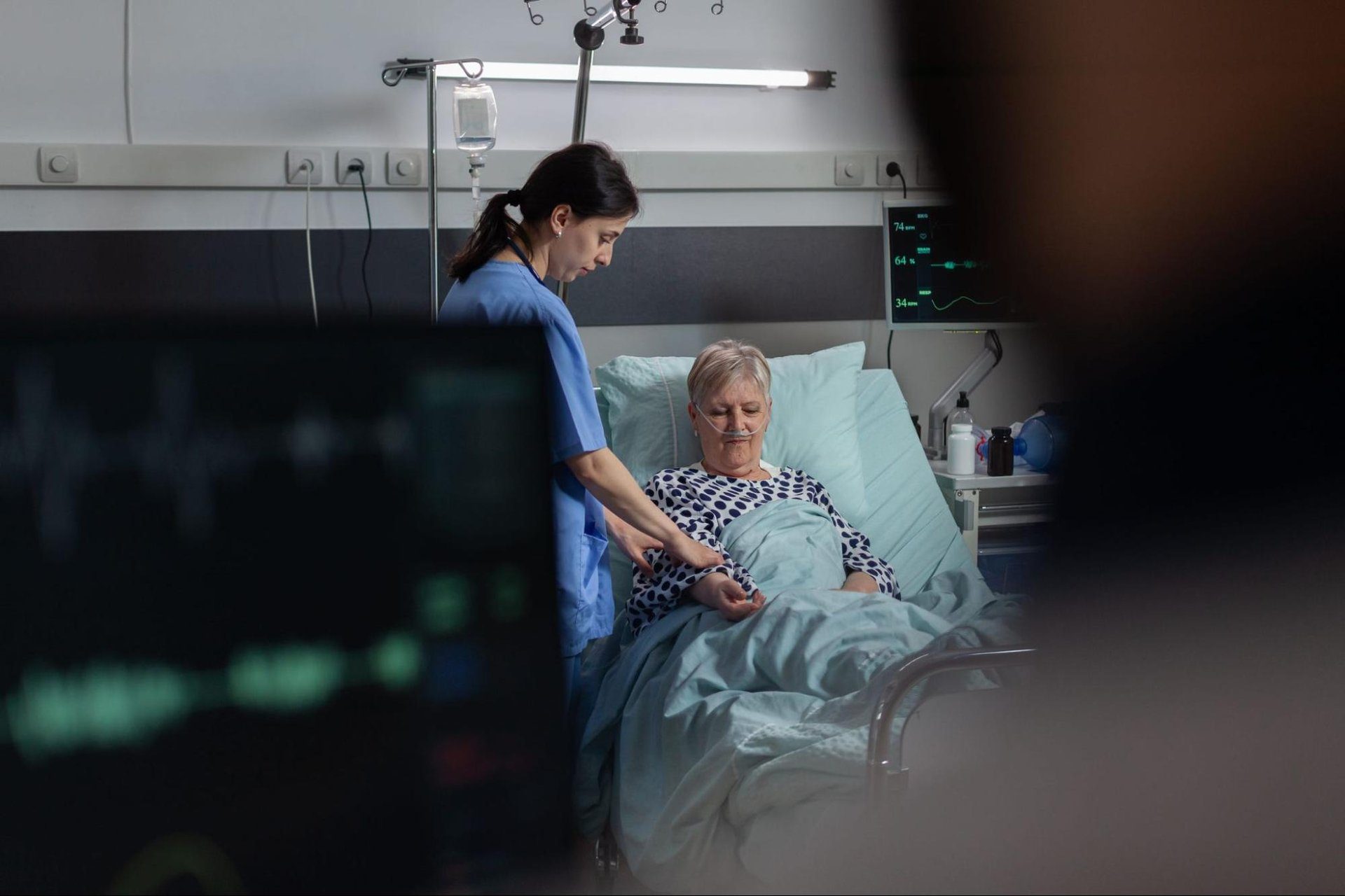 Emergency room nurse checking on an older patient resting in a hospital bed