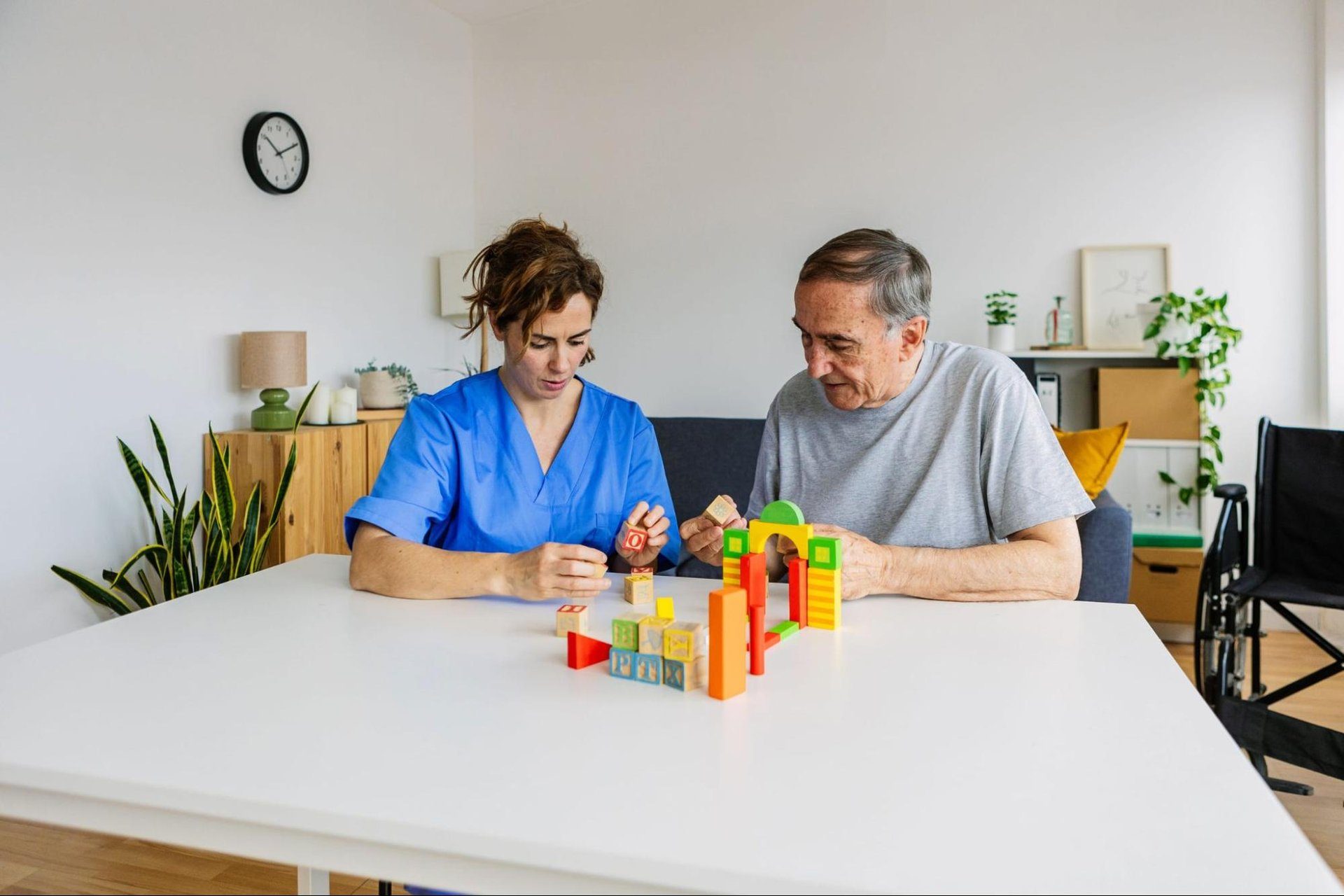 Occupational therapy assistant working with an older man on a building block exercise at a table